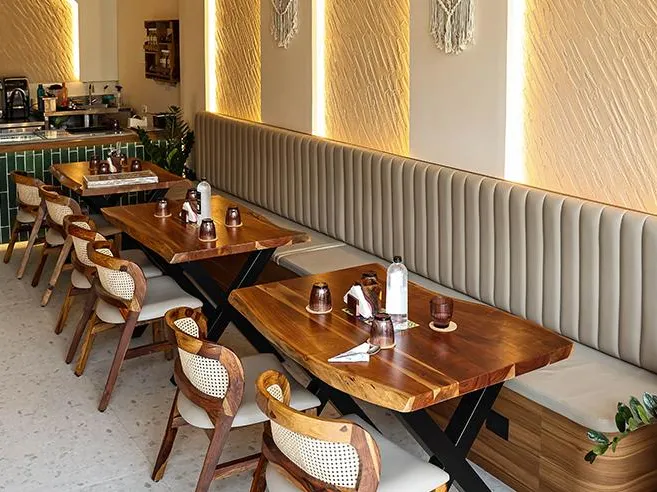 A café with a live-edge wooden table, upholstered banquette and chairs