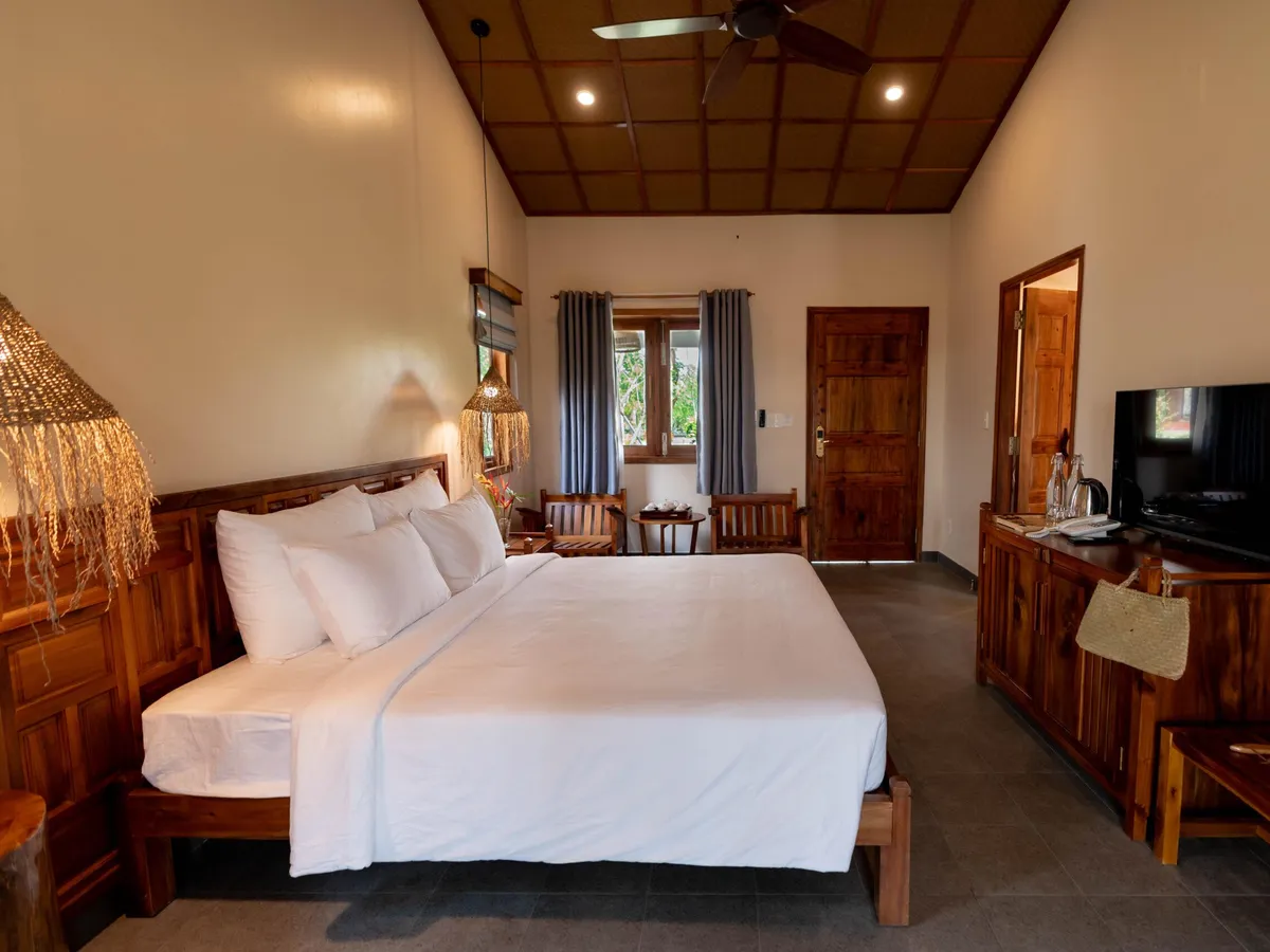 A hotel room with a wooden bed, cabinet and warm timber ceiling