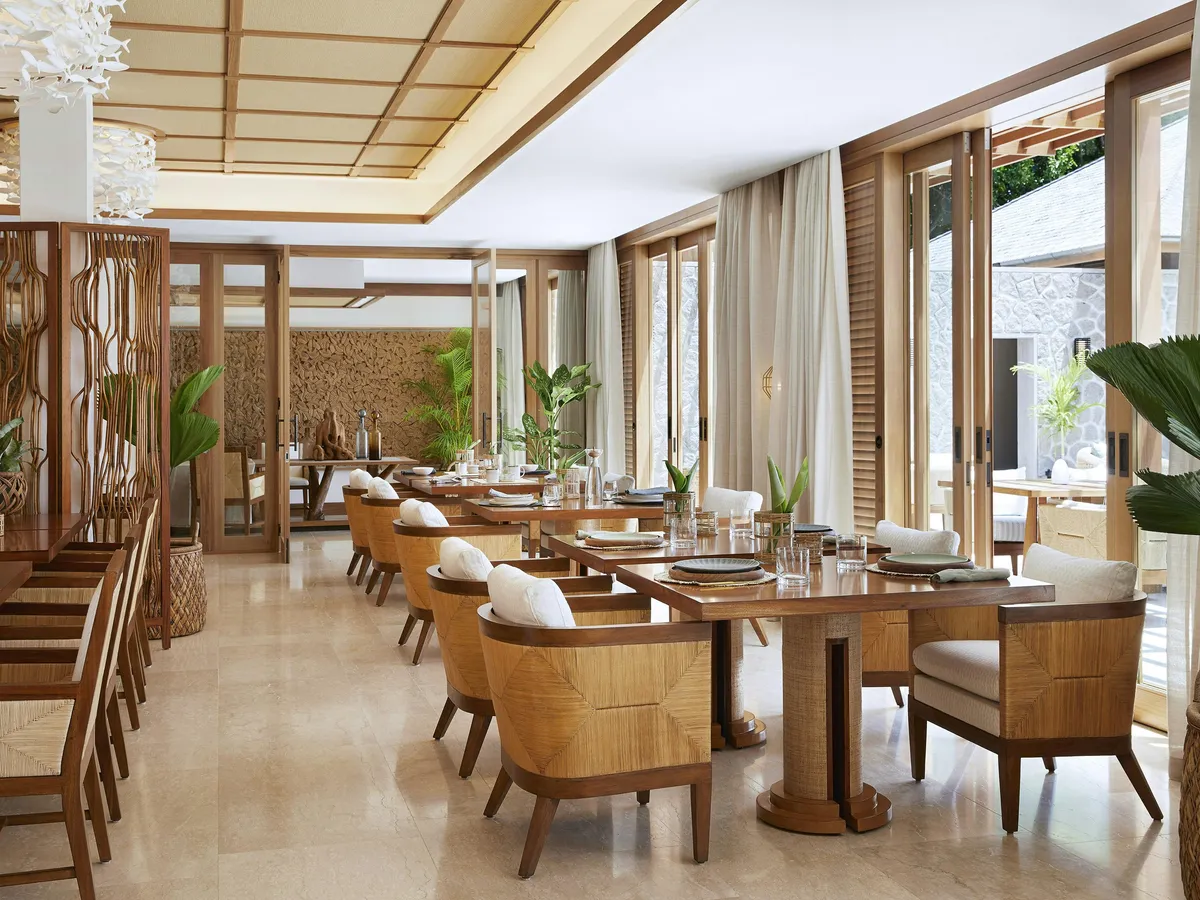 A restaurant dining room with wooden tables and cane-backed armchairs
